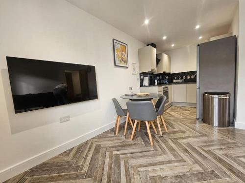 a kitchen with a table and chairs and a television on a wall at Apollo 16-1 bed town center in Luton