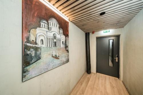 a hallway with a painting on the wall next to a door at Zaliakalnio Terasos apartamentai 2 in Kaunas