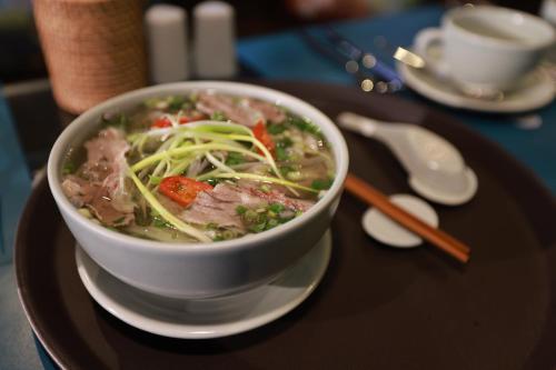 un tazón de sopa en un plato en una mesa en Kecho Legacy Hotel Hanoi & Spa, en Hanói