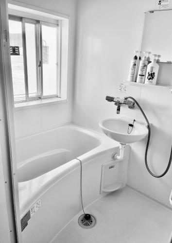a white bathroom with a sink and a bath tub at 飯野小屋 in Marugame