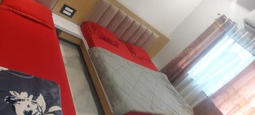 a red bed in a room with a window at Hotel Bholenath, Omkareshwar Near Gajanand Ashram in Godarpura