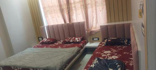 two beds sitting in a room with a window at Hotel Bholenath, Omkareshwar Near Gajanand Ashram in Godarpura