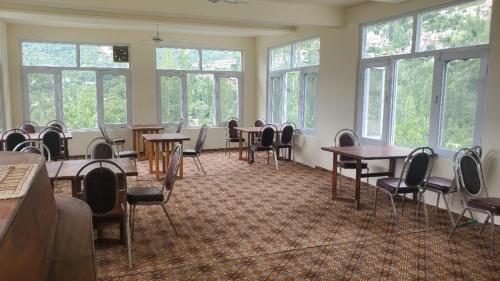 a conference room with tables and chairs and windows at Ultar House in Karimabad Hunza