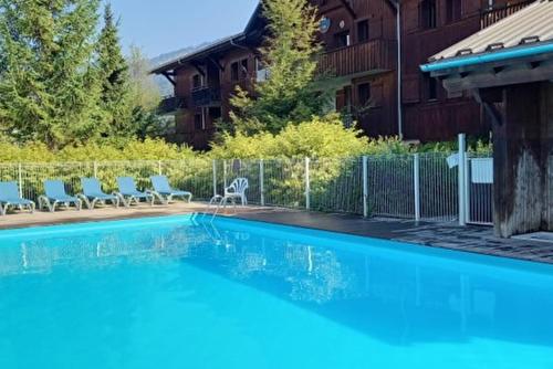 une piscine avec des chaises et un bâtiment dans l'établissement Les Fermes de Samoëns, à Samoëns