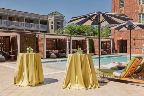 two tables with umbrellas next to a swimming pool at The Alida, Savannah, a Tribute Portfolio Hotel in Savannah