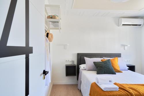 a white bedroom with a bed with orange pillows at RG Duque de Aveiro in Málaga