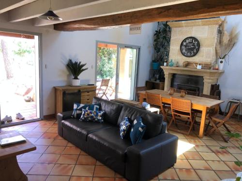 un salon avec un canapé noir et une table dans l'établissement Villa TAKY - LE VERDON SUR MER - max 11 pers, au Le Verdon-sur-Mer