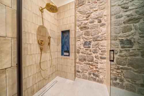 a bathroom with a shower with a stone wall at Hotel Brattia, Adults Only, Heated Pool, A la Carte Breakfast, Postira, Brač Island in Postira