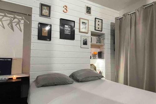 - une chambre dotée d'un lit blanc avec des photos sur le mur dans l'établissement Appartement Plage de Ferrieres, à Martigues