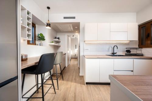 a kitchen with white cabinets and bar stools at Latour Inspired by Elegance in (( Kermetés ))