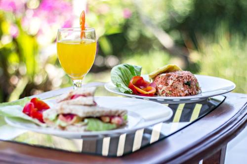 a table with two plates of food and a glass of orange juice at Graha Rusni in Ubud