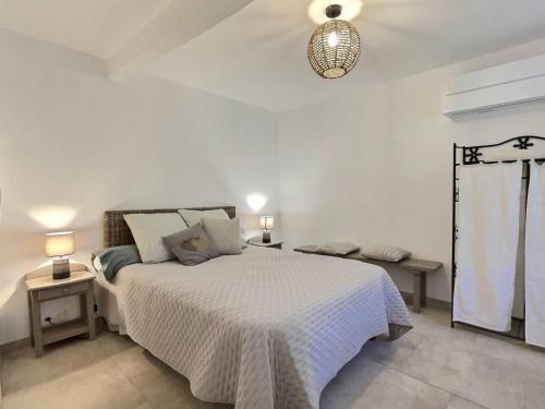 a white bedroom with a bed and a lamp at La Petite école du Valdeyron in Valleraugue