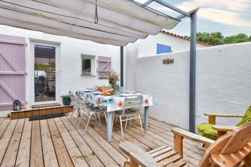 un patio avec une table et des chaises sur une terrasse dans l'établissement Jolie maison pour 7 - 300 m de la plage - Dunes, à La Guérinière