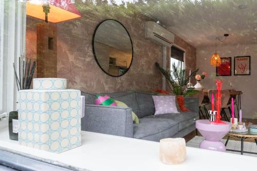 un soggiorno con un divano grigio e uno specchio di Boutique Chalet Putten op de Veluwe a Krachtighuizen