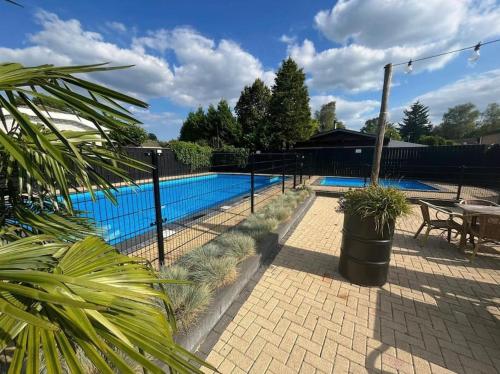 a fence around a pool with a table and a bench at Boutique Chalet Putten op de Veluwe in Krachtighuizen