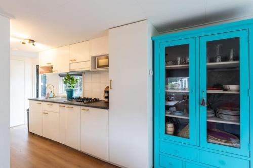 a kitchen with white cabinets and blue doors at Boutique Chalet Putten op de Veluwe in Krachtighuizen