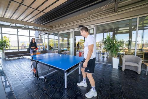 a man standing in front of a ping pong table at Hotel Aura Design & Garden Pool in Prague