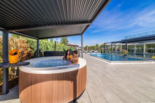 two people sitting in a hot tub next to a pool at Hotel Aura Design & Garden Pool in Prague