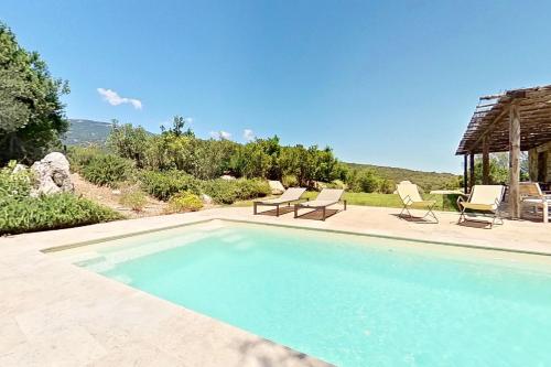 a swimming pool with two chairs and a table at ARGIALE - ARGHJALE in Figari