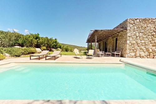 a swimming pool in front of a stone house at ARGIALE - ARGHJALE in Figari