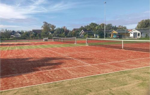 a tennis court with a net on a dirt court at De Frije Fûgel - Een luxe chalet op De Friese Wadden in Tzummarum