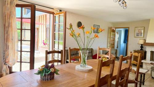 a dining room table with a vase of flowers on it at Le Malis - Charming half-timbered family house with large garden in Saint-Jouin