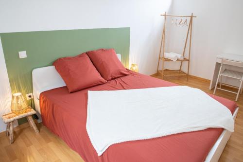 - une chambre dotée d'un grand lit avec des draps rouges et blancs dans l'établissement Charmant duplex T3 centre historique Muret, à Muret