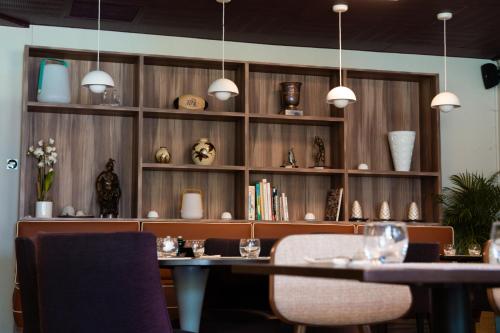 a dining room with a table and shelves with vases at Hôtel du Golf Saint Lazare in Limoges