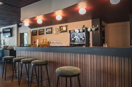 a bar with four stools at a bar at Hôtel du Golf Saint Lazare in Limoges