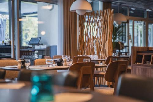 a restaurant with wooden tables and chairs and windows at Hôtel du Golf Saint Lazare in Limoges