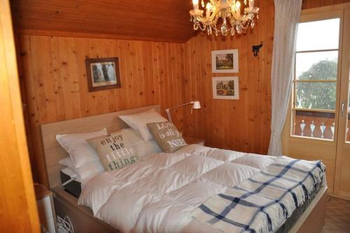 Un dormitorio con una cama grande con una lámpara de araña. en Héloïse, en Arveyes