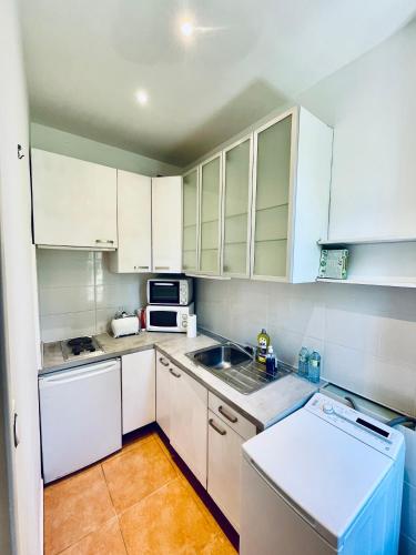 une petite cuisine avec des armoires blanches et un évier dans l'établissement Cimiez studio aperçue Mer, à Nice