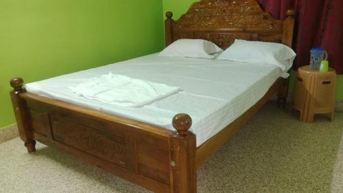 a wooden bed with white sheets and white pillows at Square & Dormitory Stays in Tirunelveli