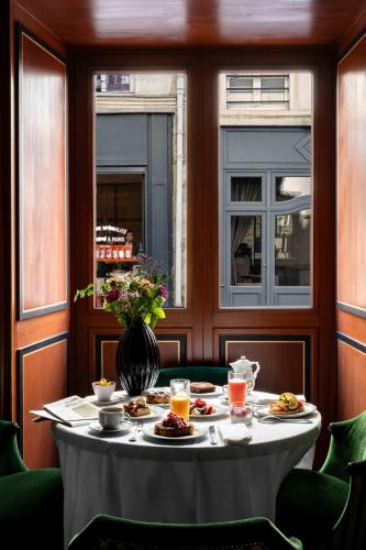 a table with plates of food on it in a room with windows at La Chambre du Marais in Paris