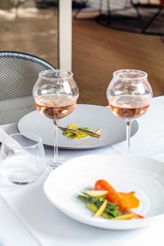 a table with two glasses of wine and a plate of food at La Prévôté - Hôtel Particulier & Restaurant in LʼIsle-sur-la-Sorgue