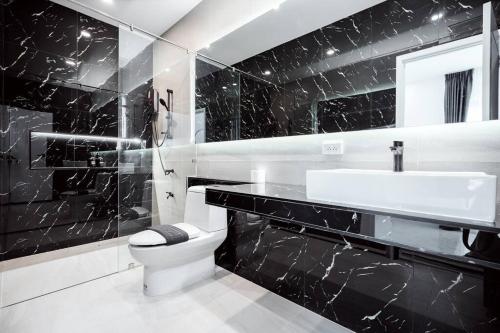 ein schwarz-weißes Badezimmer mit Toilette und Waschbecken in der Unterkunft Sea'cret Stay Villa Pattaya พัทยา พูลวิลล่าพัทยา ใกล้ทะเล in Na Jomtien