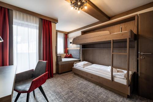 a hotel room with a bunk bed and a chair at Hotel Alpenrose in Zauchensee