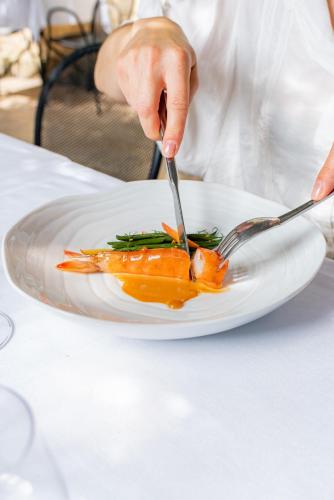 a person eating a plate of food with a fork and knife at La Prévôté - Hôtel Particulier & Restaurant in LʼIsle-sur-la-Sorgue