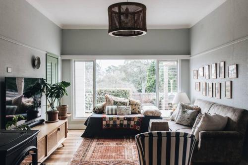 a living room with a couch and a large window at Seymour House in Moss Vale