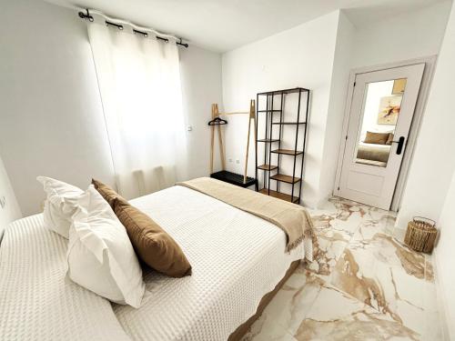 a white bedroom with a bed and a marble floor at Vivienda turística Jaén Interior ÁTICO in Andújar