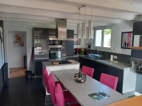 - une cuisine avec une table et des chaises roses dans l'établissement La Villa Kerleven, à La Forêt-Fouesnant