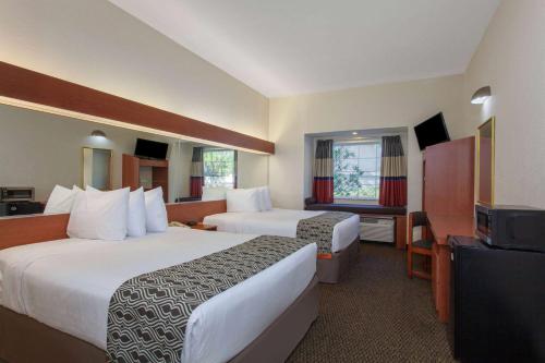 a hotel room with two beds and a flat screen tv at Microtel Inn and Suites by Wyndham - Lady Lake/ The Villages in The Villages