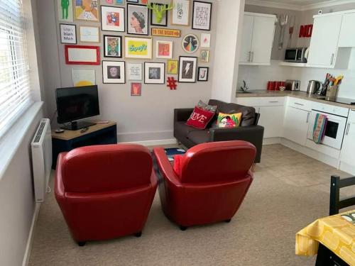 a living room with two red chairs and a couch at Jurassic Coast Holiday Home in Charmouth
