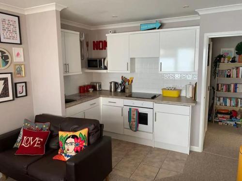 a kitchen with white cabinets and a couch in a living room at Jurassic Coast Holiday Home in Charmouth