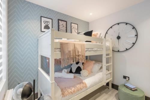 a room with bunk beds with a clock on the wall at Unwind in Style 2BR with Cozy Backyard for Groups in London