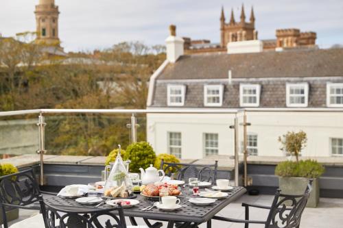 a table with plates of food on a balcony at The Old Government House Hotel & Spa in St Peter Port