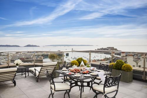 a table and chairs on a balcony with a view of the ocean at The Old Government House Hotel & Spa in St Peter Port