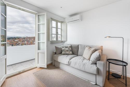 a living room with a couch and a large window at GuestReady - Riverview Douro Balcony in Vila Nova de Gaia