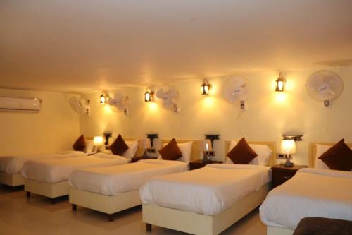 a hotel room with three beds and lights on the wall at Satshree Kothi in Varanasi