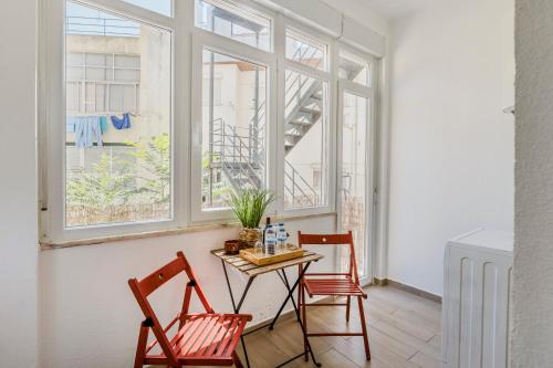 a table and two chairs in a room with windows at All2gether Apartment in Lisbon
